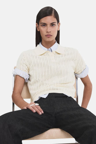 Polo beige de MANGO, porté sur une chemise bleu clair et associé à un pantalon foncé.