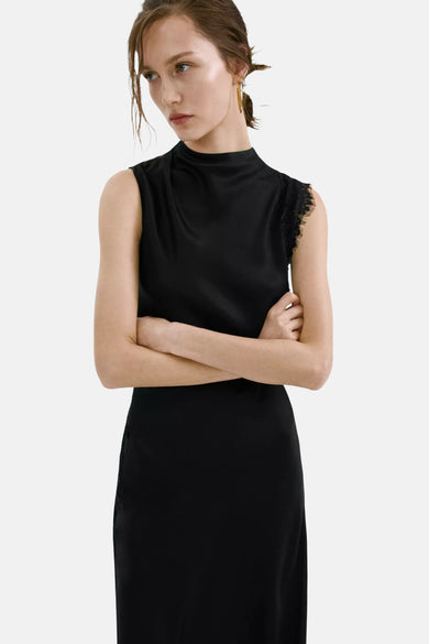 Robe noire sans manches de MANGO avec col montant, tissu soyeux et détail en dentelle sur l'épaule.
