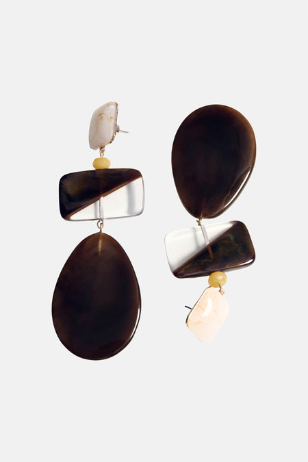 Multikleurige oorringen van MANGO, met diverse vormen en kleuren zoals bruin en wit, hangend aan gouden details.
