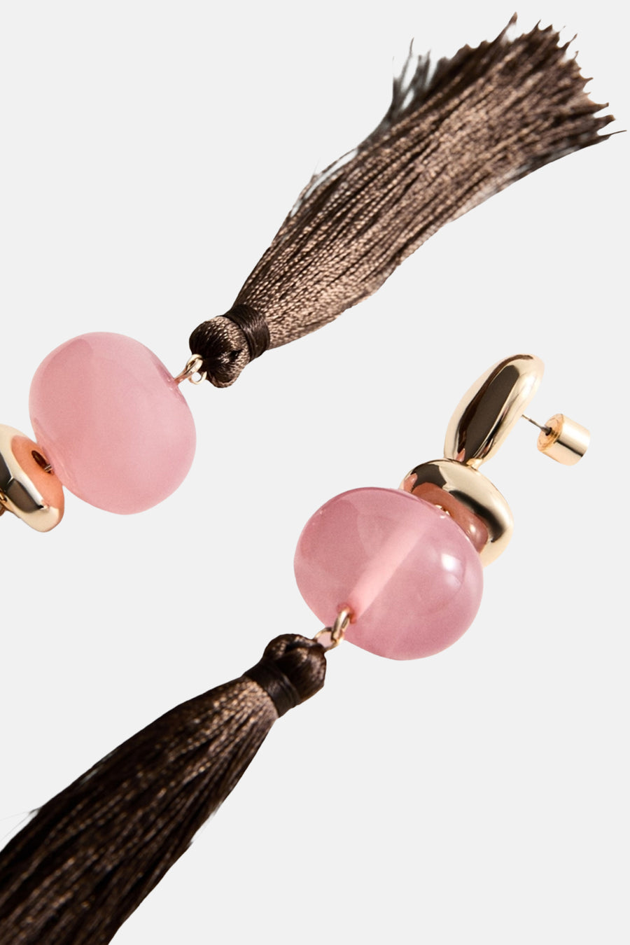 Multikleurige oorringen van MANGO, met roze stenen en bruine kwasten, in een schuine weergave.
