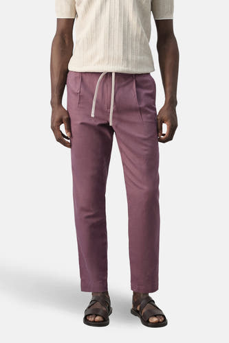 Pantalon violet de MANGO, vu de dos, avec un t-shirt beige et des sandales marron.