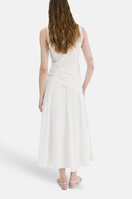 Ecru mouwloos kleedje van MANGO met geborduurd paneel rond de taille, van achteren gezien met sandalen.