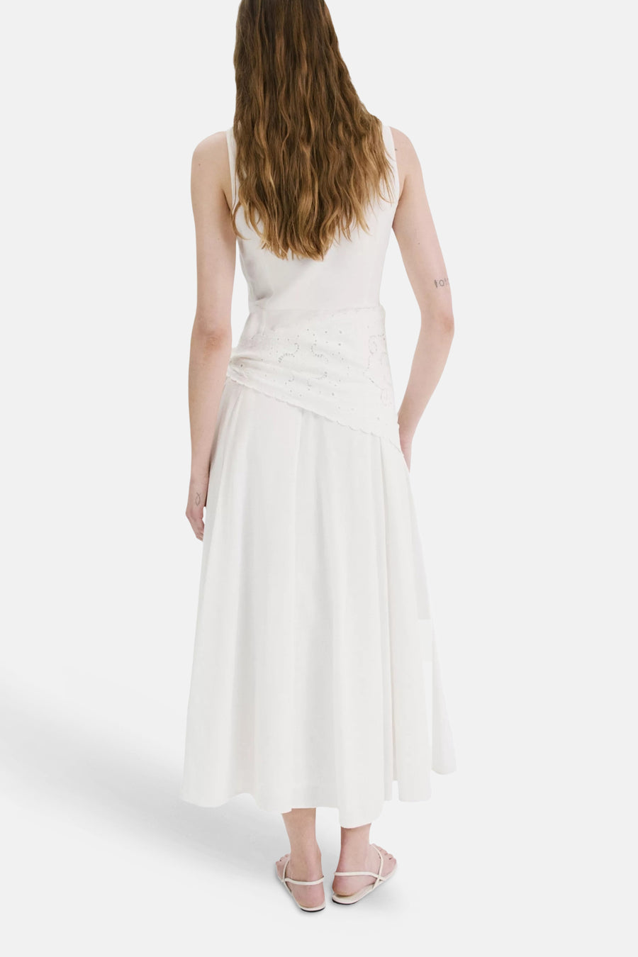 Ecru mouwloos kleedje van MANGO met geborduurd paneel rond de taille, van achteren gezien met sandalen.