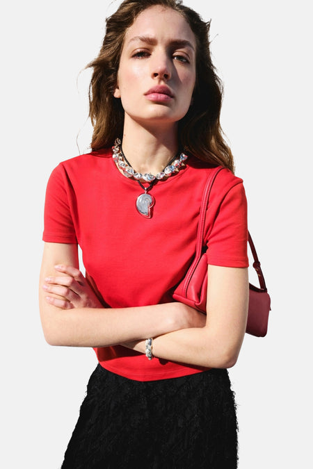 Rood T-shirt met korte mouwen van MANGO, gestyled met een zwarte rok, zilveren ketting en rode schoudertas.