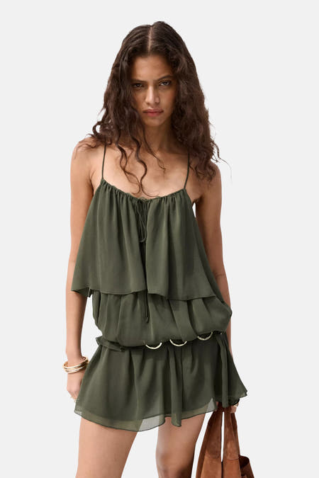 Groen mouwloos kleedje van MANGO met ruches, spaghettibandjes, gouden ringen op de taille, gouden armbanden en een bruine tas.