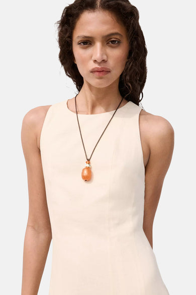 Beige mouwloos jurkje van MANGO, strak model met ronde hals, gedragen met oranje hanger, front view
