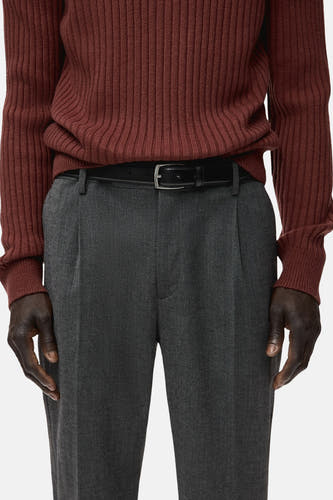 Pantalon gris de MANGO, avec plis et une ceinture en cuir noire.