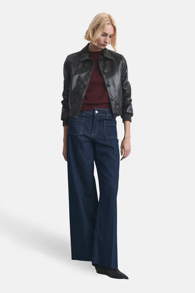 Wijde jeans van donkerblauw denim van MANGO, gecombineerd met een donkere leren jas en bordeauxrode top.