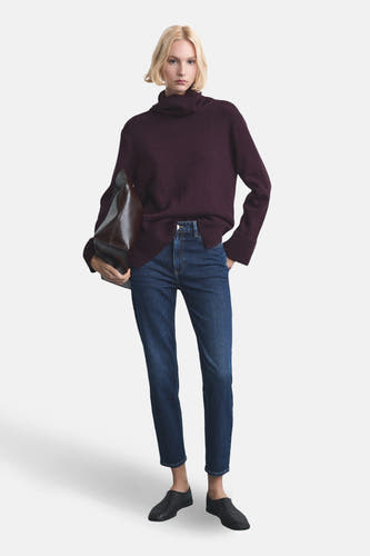 Donkerblauwe mom jeans van denim van MANGO, gecombineerd met een bordeauxrode coltrui en zwarte schoenen.