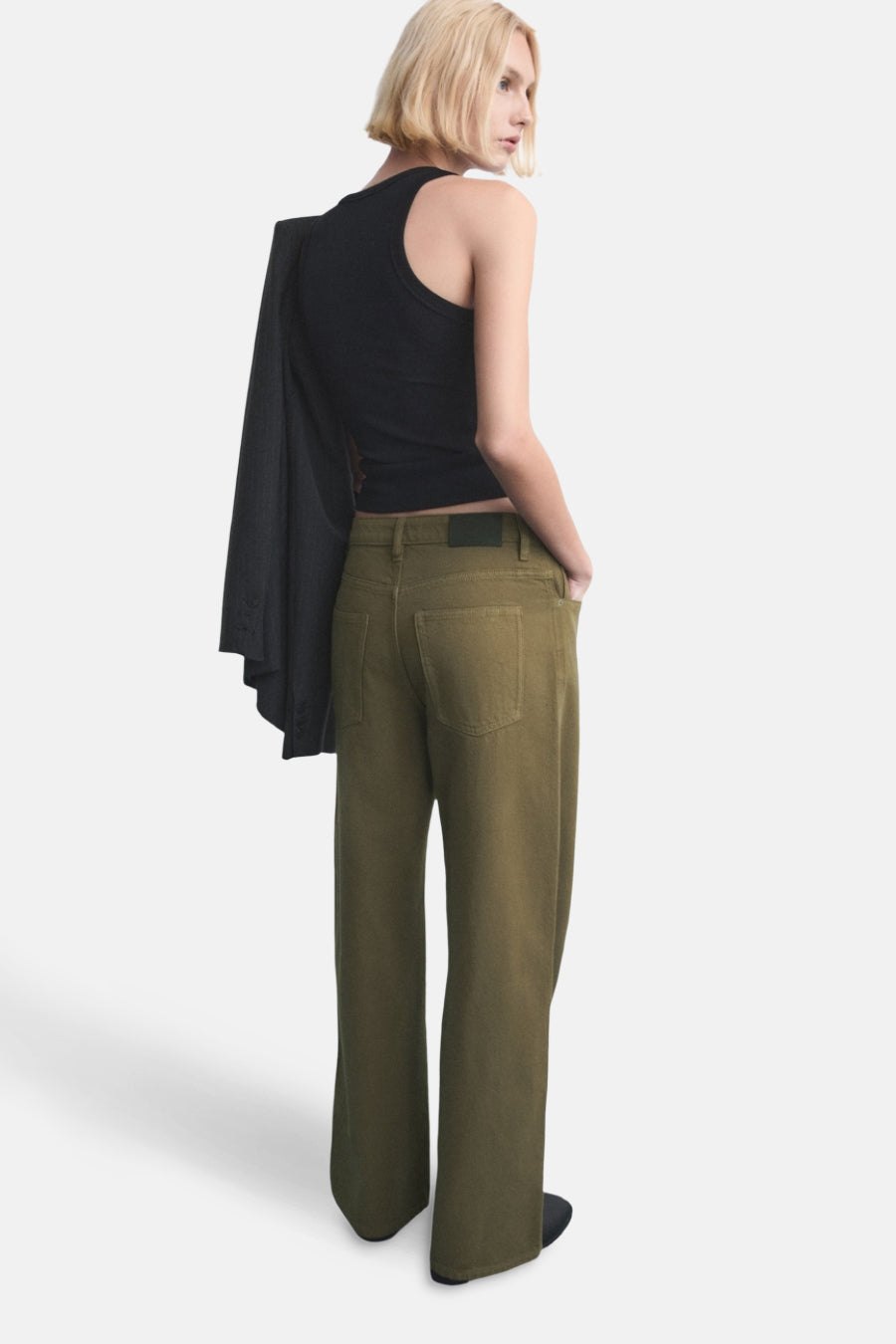 Kaki gekleurde jeans van MANGO, met wijde pijpen en achterzakken, gecombineerd met een zwarte top en blazer over de schouder.