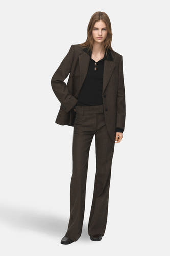 Pull noir avec col rond de MANGO, associé à un manteau tweed deux brun.