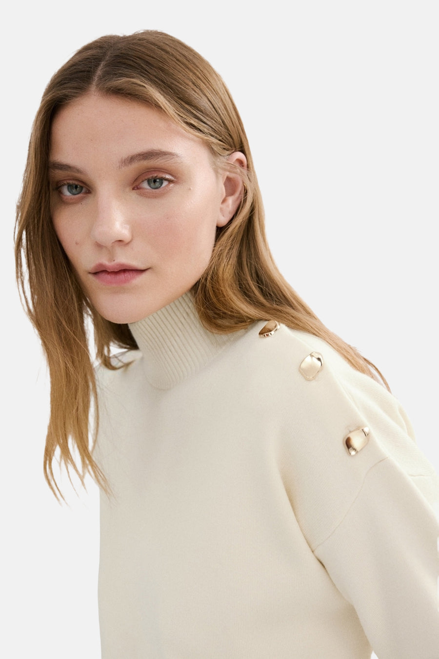 Ecru trui met ronde hals van MANGO, afgewerkt met sierknopen op de schouder.
