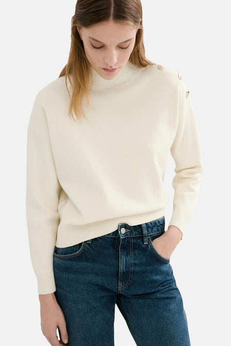 Pull de couleur écru à col rond de MANGO, à manches longues, combiné avec un jean bleu.