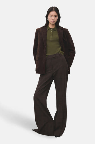 Pull khaki avec col rond de MANGO, porté avec un blazer marron et une jupe à carreaux.