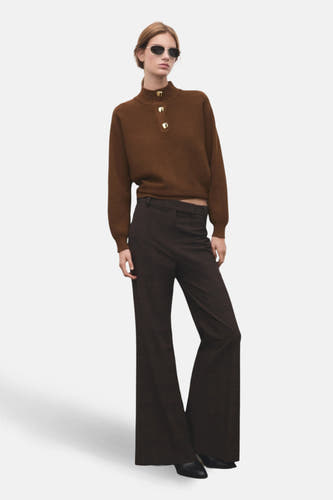 Pull à col roulé marron de MANGO, avec des manches longues et des boutons dorés sur le cou, associé à un pantalon marron.