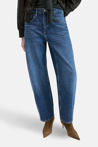 Jean en denim bleu moyen coupe spéciale de MANGO, combiné avec une veste en cuir noire et des bottines en daim marron.