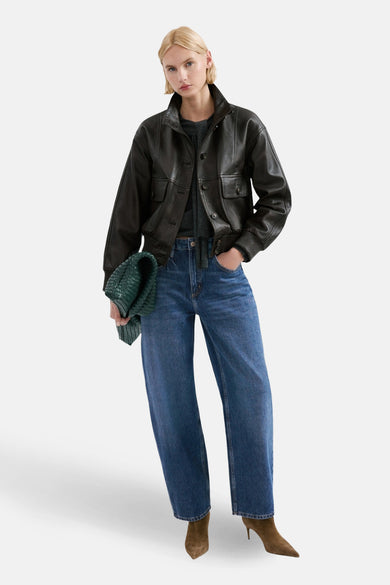 Jean en denim bleu moyen coupe spéciale de MANGO, avec jambes larges et bottines marron.