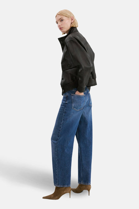 Middenblauwe denim jeans special fit van MANGO, gecombineerd met een zwarte leren jas en bruine suède laarsjes.
