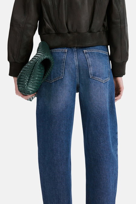 Middenblauwe denim jeans van MANGO, gezien van achteren, met wijde pijpen en groene tas.