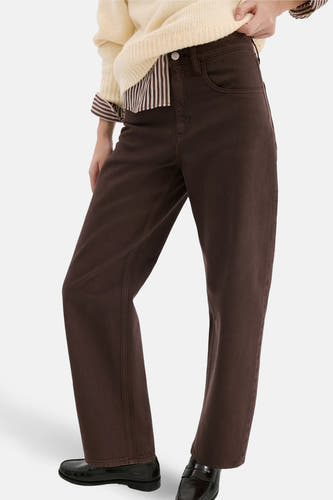 Jean bleu de MANGO, décontracté et avec des poches, associé à une chemise crème et à des chaussures noires.