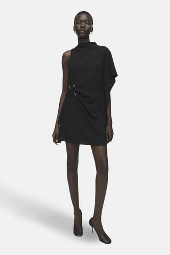 Robe noire sans manches de MANGO, avec une encolure asymétrique et un drapé décoratif sur le côté.