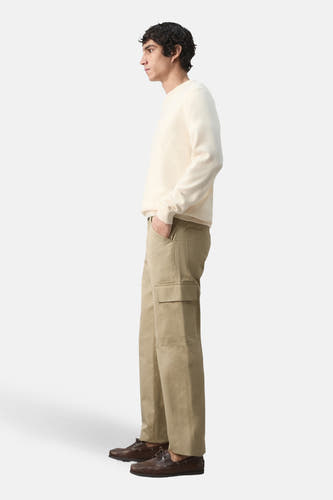 Beige broek van MANGO, met cargozak, gecombineerd met een crèmekleurige trui en bruine schoenen, in zij-aanzicht.
