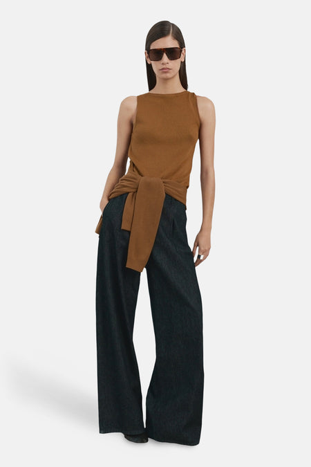 Haut sans manches marron de MANGO, noué à la taille, avec un pantalon long foncé et des lunettes de soleil.