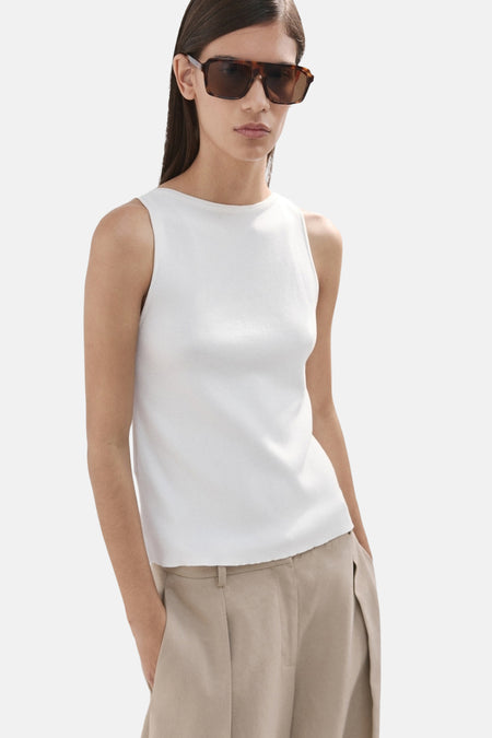 Haut sans manches écru de MANGO, avec une silhouette ajustée et de longs cheveux bruns dans le dos.