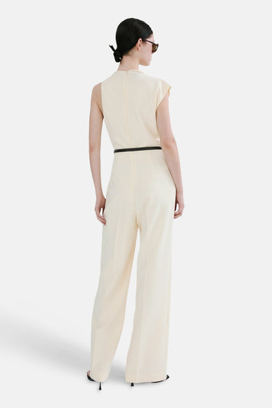 Ecru jumpsuit van MANGO, met een zwarte riem en wijde pijpen, gezien van achteren.