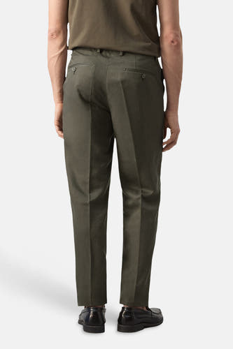 Khaki broek van MANGO, gezien van achteren, met steekzakken en geklede schoenen.
