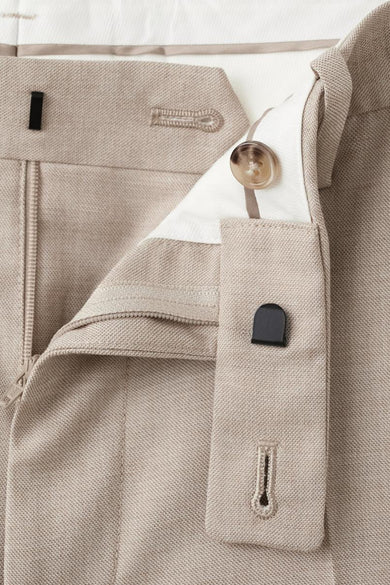 Beige kostuumbroek van MANGO, met een gedeeltelijk geopende ritssluiting en knoopsluiting.