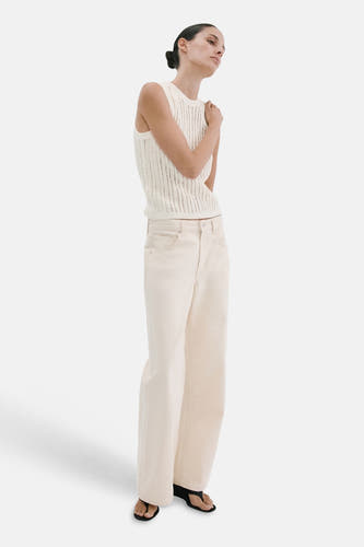Mouwloze ecru top van MANGO, met open gebreide textuur, gecombineerd met wijde crèmekleurige jeans en sandalen.