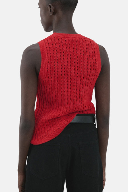 Rode mouwloze top van MANGO, met een opengebreide textuur, gecombineerd met een zwarte broek en riem.
