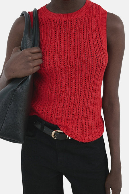 Mouwloze rode top van MANGO, met opengebreid patroon en gecombineerd met een zwarte broek en tas.
