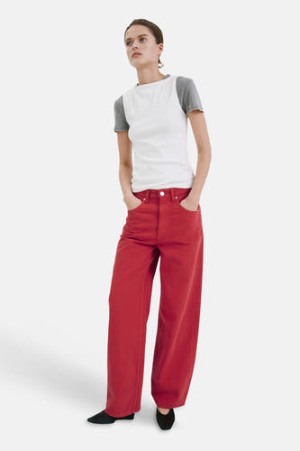 Jean de couleur rouge de MANGO à jambes larges, porté avec un t-shirt blanc cassé et des chaussures noires.