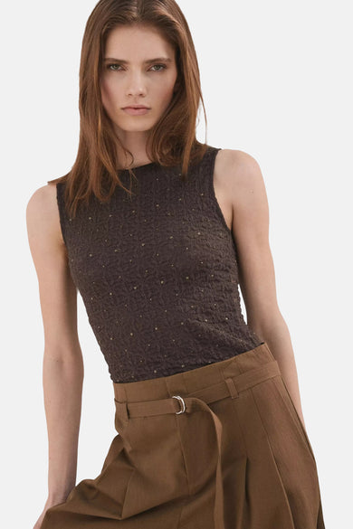 Bruine mouwloze top van MANGO met een gestructureerd patroon en glimmende stippen, gecombineerd met een bruine pantalon.