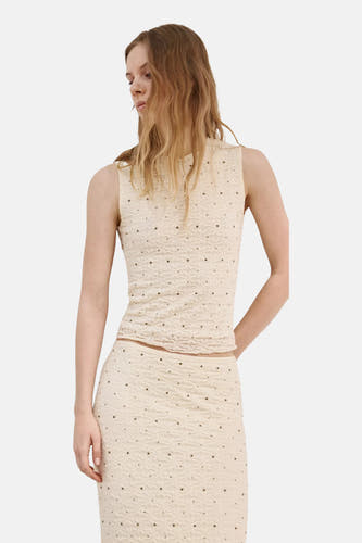 Ecru top van MANGO met mock neck, mouwloos, textuur en kleine donkere studs, gedragen met een bijpassende rok.