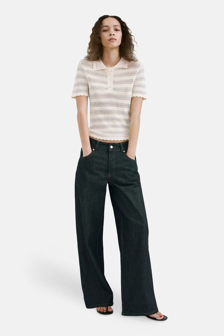 Ecru gebreide polo van MANGO met strepen, kraag en geschulpte randen, gedragen door een model met donkere jeans.