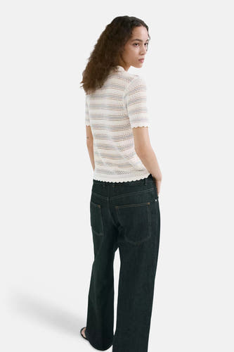 Ecru polo van MANGO met gestreepte gebreide stof, korte mouwen en geschulpte randen, achterkant op model met donkere jeans.