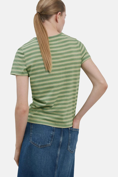 Gestreept groen T-shirt van MANGO, achterkant van model met blonde paardenstaart en hand in blauwe spijkerbroekzak.