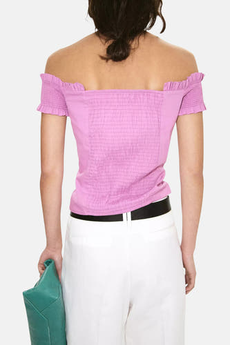 Roze blouse met korte mouwen van MANGO, rugzijde met ruches en plooien, model draagt witte broek en zwarte riem