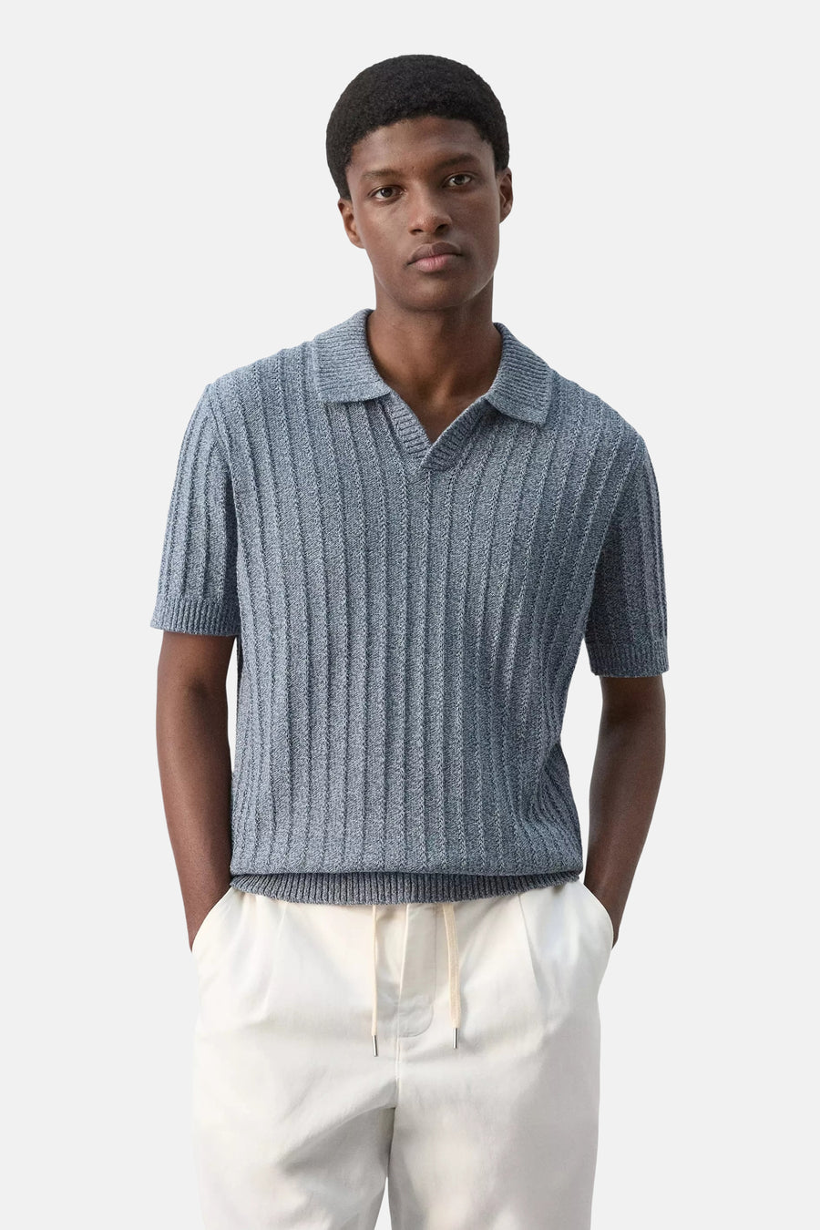Blauwe gebreide polo met ribstructuur van MANGO, gedragen door model met witte broek, front view