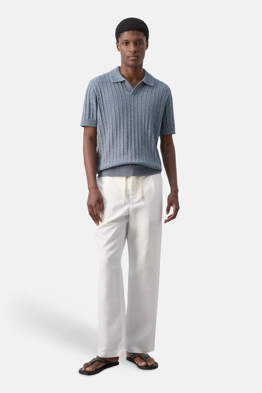 Blauwe gebreide polo met ribstructuur van MANGO, gedragen met witte broek en slippers, front view