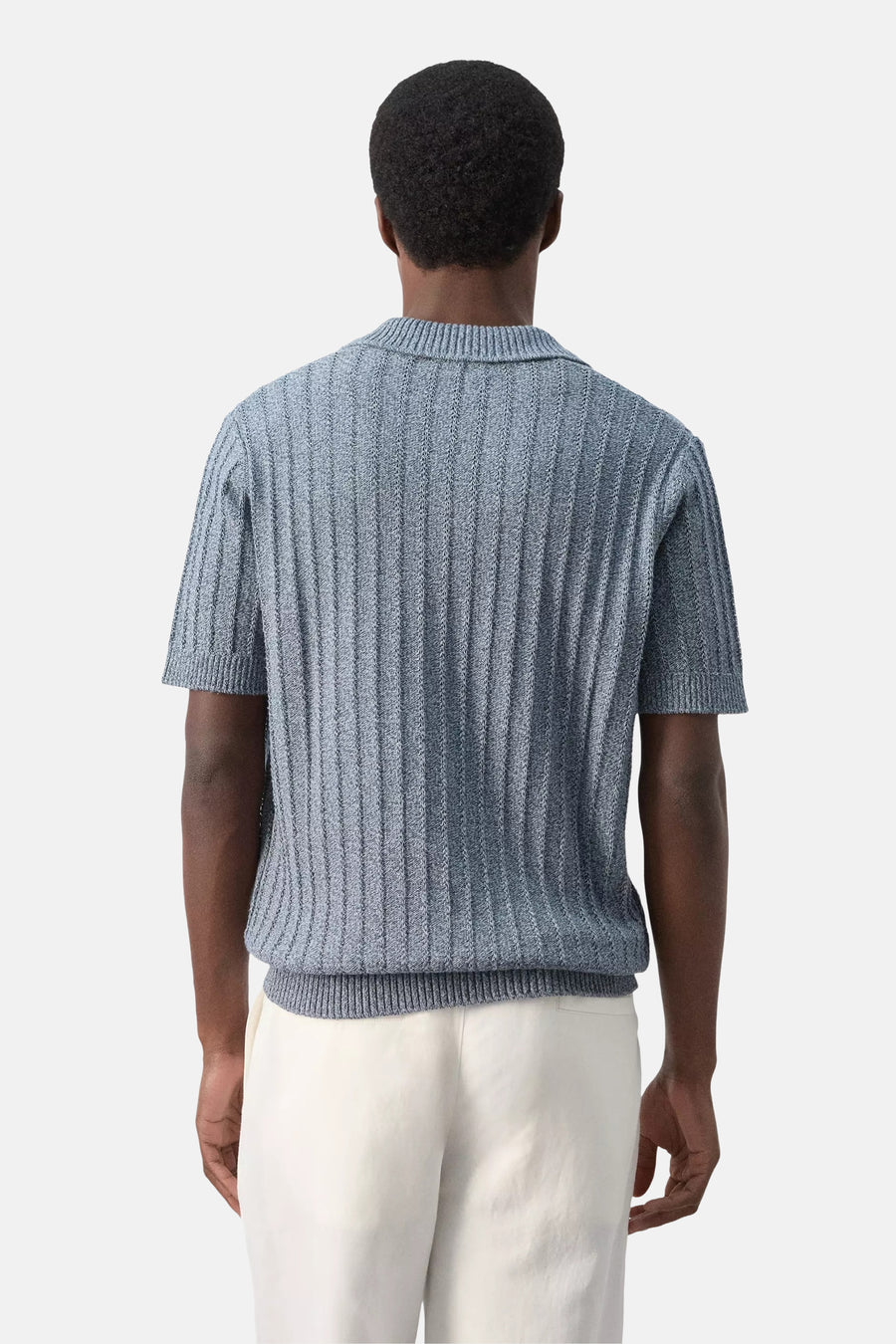 Blauwe gebreide polo van MANGO, met verticale ribstructuur, achterkant, korte mouwen, witte broek
