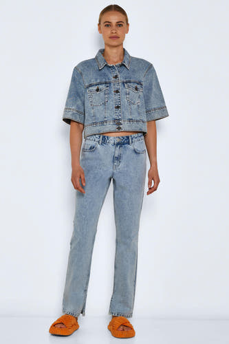 Rechte jeans van lichtblauw denim van Noisy May, met een split aan de zoom, gecombineerd met een denim jasje en oranje slippers.