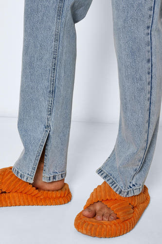 Lichtblauwe straight jeans van NOISY MAY, met splitjes bij de enkels, gecombineerd met oranje slippers.
