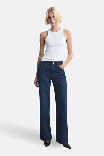Jean bleu marine droit en denim de MANGO, avec un chemisier blanc et des chaussures noires.