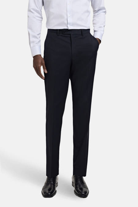 Pantalon de costume bleu MANGO, vu vu l'arrière, avec poches et passants de ceine, associé à une chemise blanche et des chaussures noires.