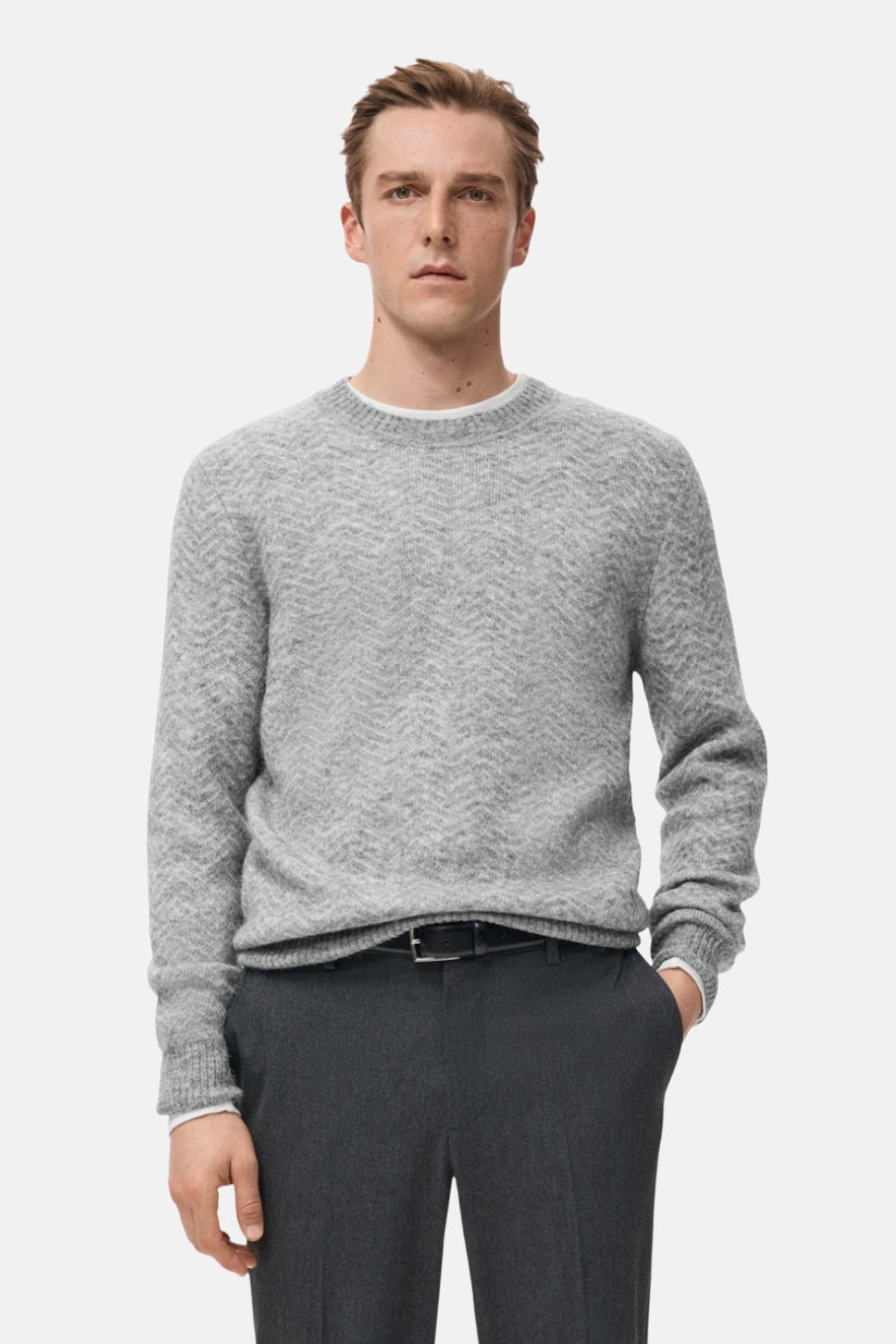 Sweat-shirt gris à col rond de MANGO, avec un motif subtil en maille fine, porté avec un pantalon foncé.