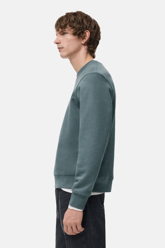 Pull-over bleu avec col rond de MANGO, vu de côté, avec une subtile texture et des manches longues.